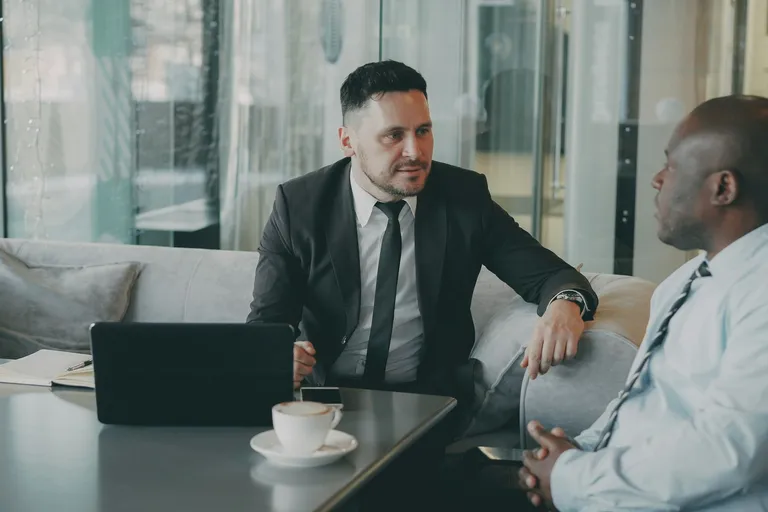 Dois homens de negócio conversando numa mesa com notebook