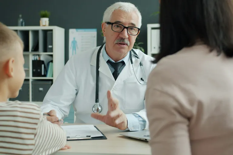 Médico atendendo uma mãe e o filho no consultório