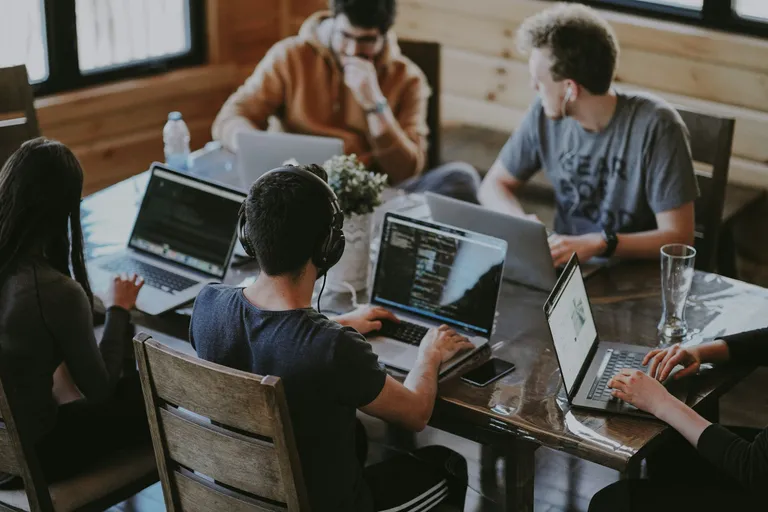 Equipe reunida em volta de uma mesa, cada um no seu notebook
