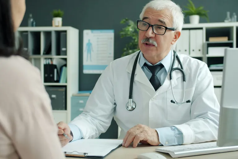 Calculadora de vidro vermelho escuro com três moedas de vidro ao lado, sobre fundo claro