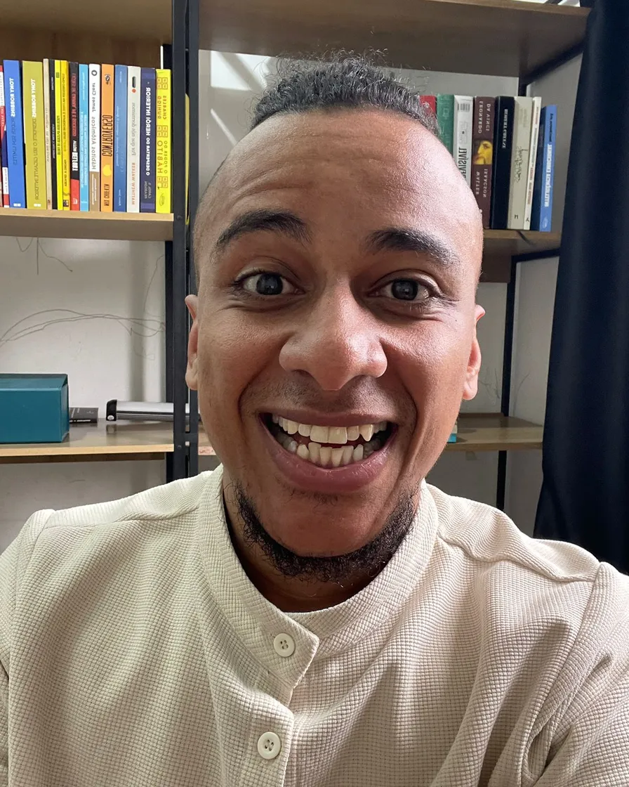 Valdemiro Ferreira sorrindo diante da estante de livros